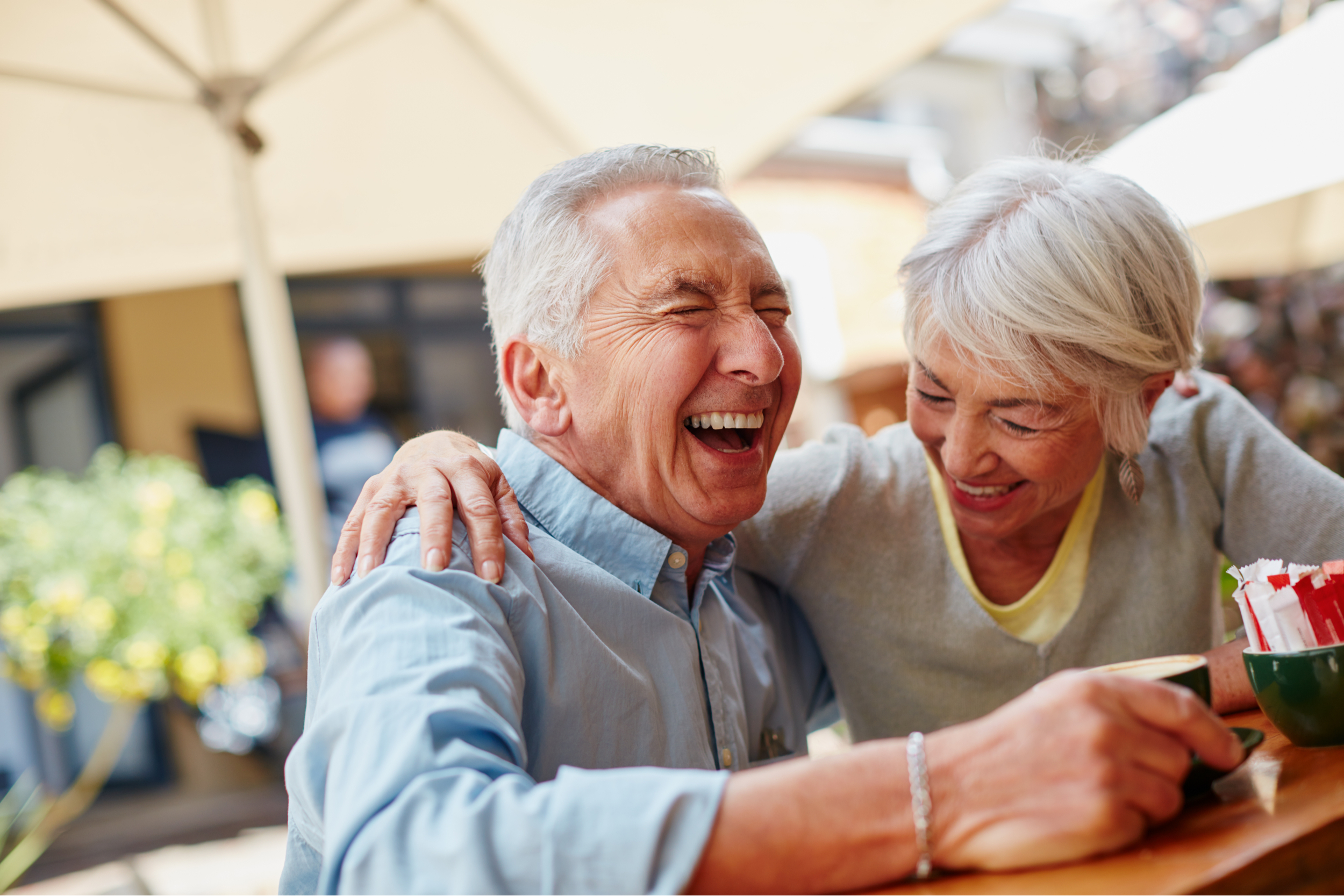 A retired couple laughing at a café.