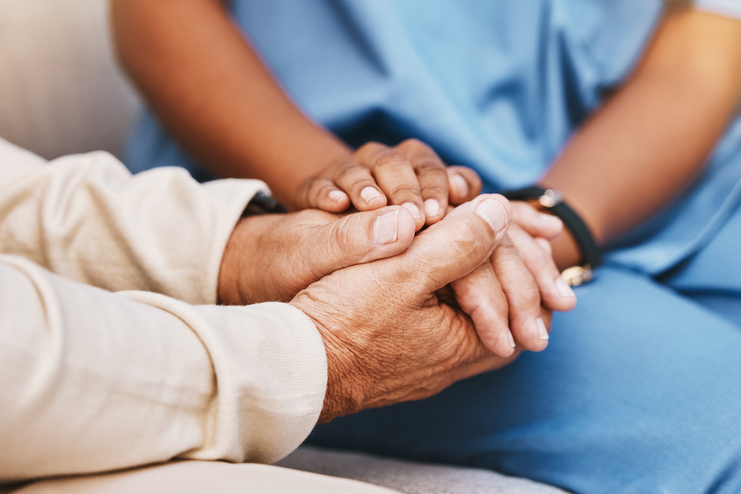 An elderly person holding hands with a nurse.