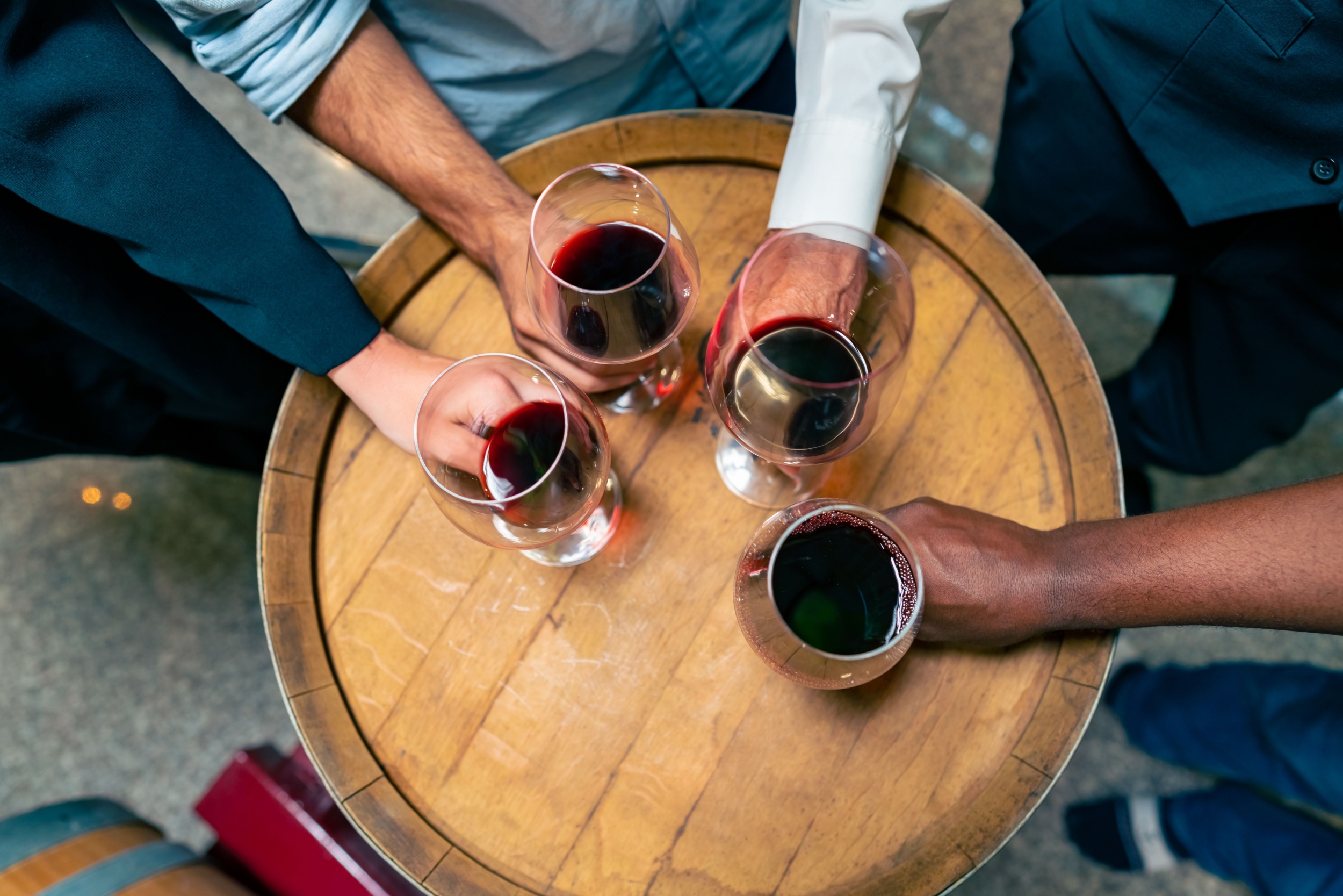 A group of people holding glasses of red wine.