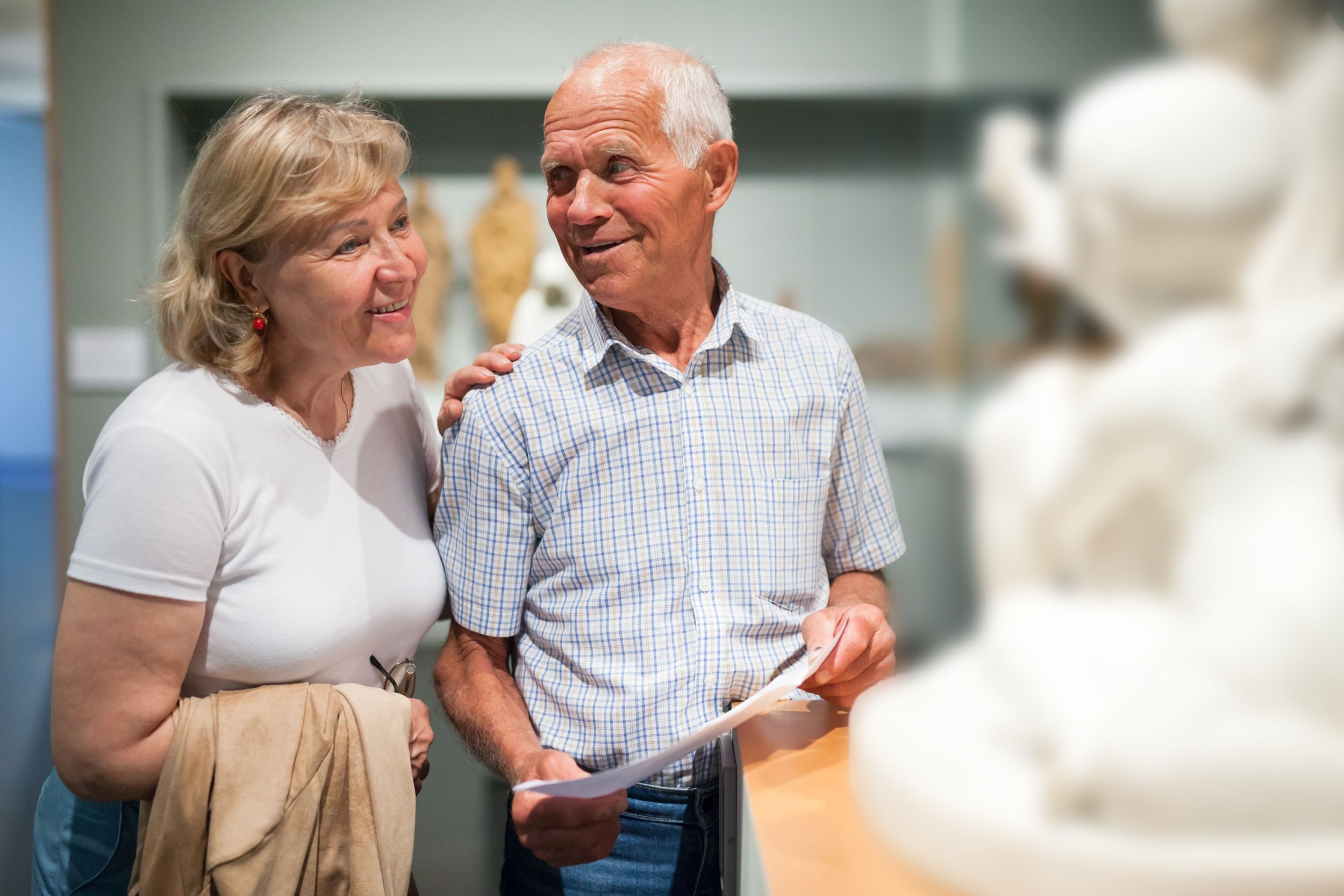 A couple looking at a statue in a museum.