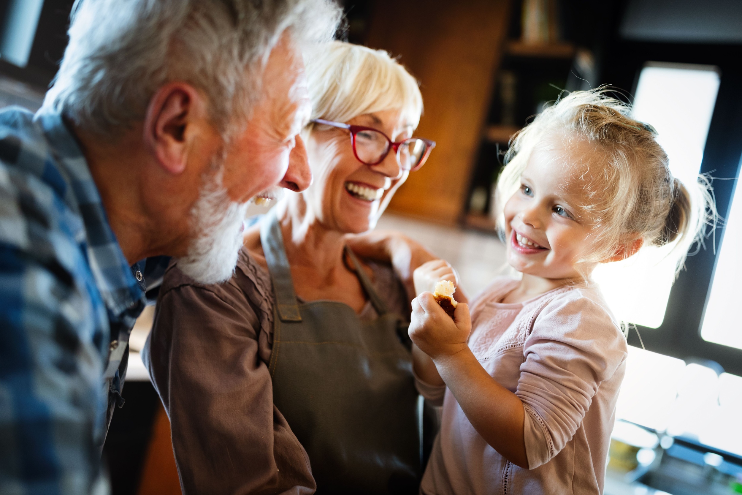 Happy smiling grandparents enjoying time with grandchild at home