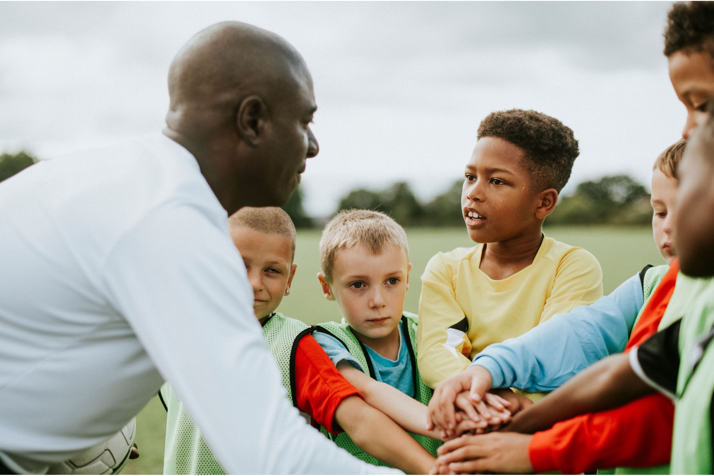 A man coaching a junior football team.
